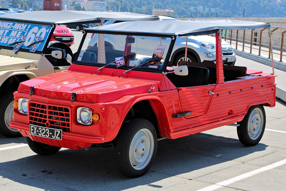 A red Citroën Méhari with black bikini top and light grey rims in front of a beach.

Source: https://commons.wikimedia.org/wiki/File:Citro%C3%ABn_M%C3%A9hari_Nice_IMG_1269.jpg
Photographer: Alexander Migl
License: Creative Commons Attribution-Share Alike 4.0 International