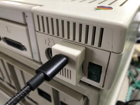 An old Apple computer with a USBC adapter in the power place