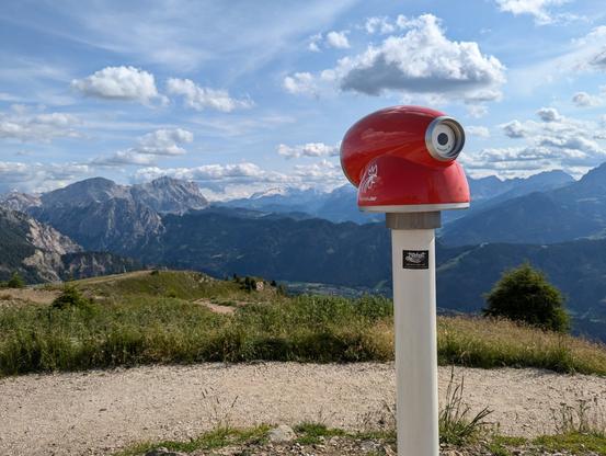 metalhead.club sticker on a white pole with a red monocular on top of the Kronplatz mountain in South Tyrol, lookin south to the Dolomites