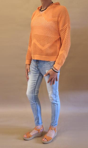 Posing with my new hole pattern sweater with a white sports bra, stonewashed jeans and my orange wedge heeled sandals. I’m also wearing a black pearl necklace and one black and one silver bracelet on my left arm. Seen from my front left.