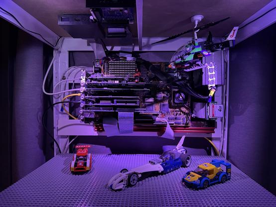 Close-up of server; shelf is covered in gray LEGO surface with a few small LEGO cars and The Joker's helicopter suspended in front of the motherboard.