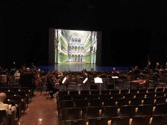 Stage with seating for large orchestra in front and a projection of the interior of the Capulet mansion