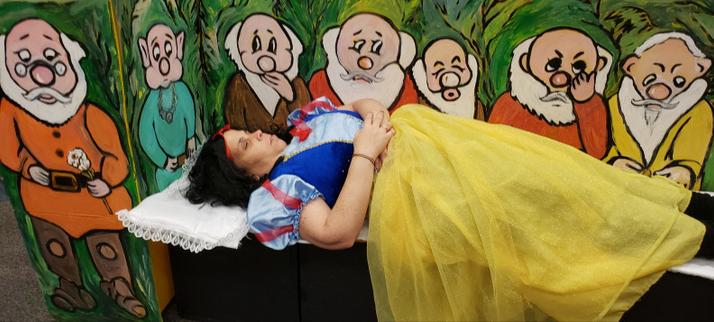 Snow White (actress) sleeps in front of a mural depicting the Seven Dwarves.