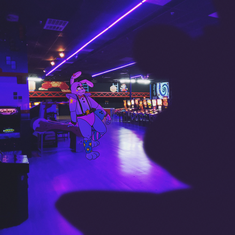 My design of glamrock bonnie leaning against a pinball machine holding a bowling ball on his hip. A silhoutte of glamrock freddy is in the foreground and we are looking over his shoulder.