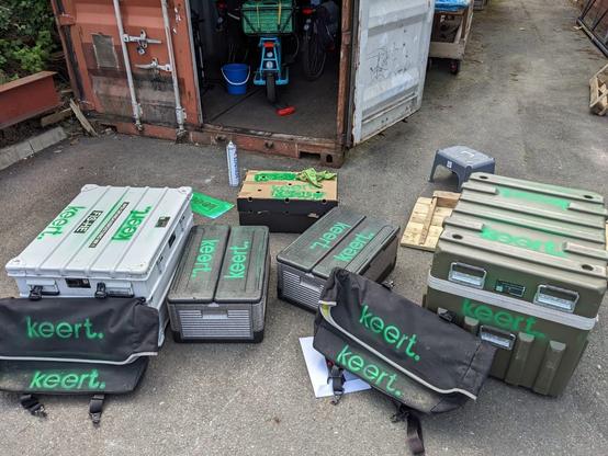 an array of boxes and bags spray painted with the word keert in bright green. Surfaces that aren't very flat show a smudged stencil