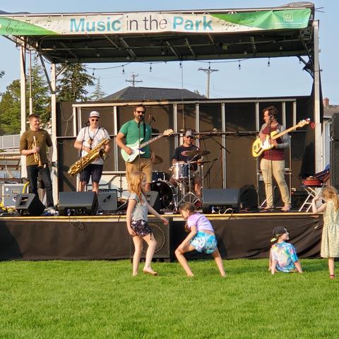 Kids dancing in front of stage. Band playing on stage.