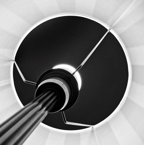 A close-up view of a circular structure. The central part is black, with three metallic arms extending outward, dividing the circle into three equal sections. The surrounding area features radial lines, suggesting it could be either the underside of a spiral staircase or part of a machine.