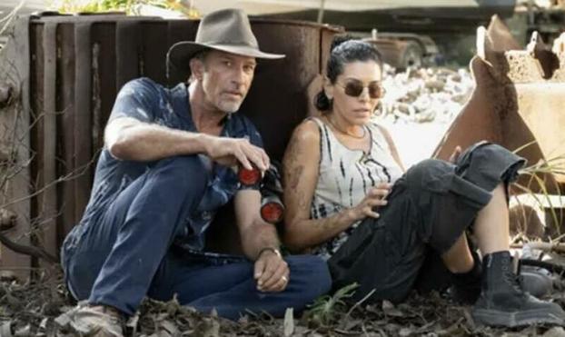 Thomas Jane and Nicole Chamoun hide behind something solid in this scene from Troppo