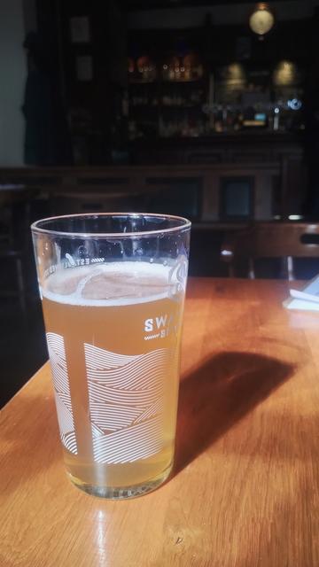 Sunlight pouring in from behind me, illuminating a pint of cloudy ale, casting a translucent shadow at an angle, like a beer sundial