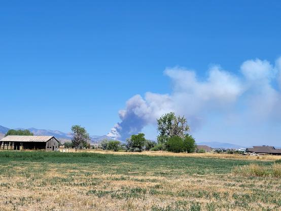 Smoke rising in the sky above a pasture