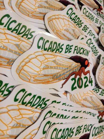 A pile of stickers of a seductive cicada that reads cicadas be fuckin 2024