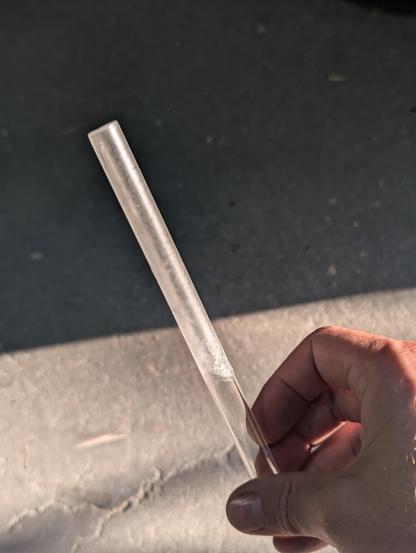 A 12mm clear glass tube (mixing stick)  seen in the sunlight against a shadow. There is a transparent, cellulose haze visible on the tube.