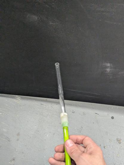 The same clear 12mm tube on a green glass holder against a black piece of plastic. The glass no longer has the transparent haze and has been burned clean.