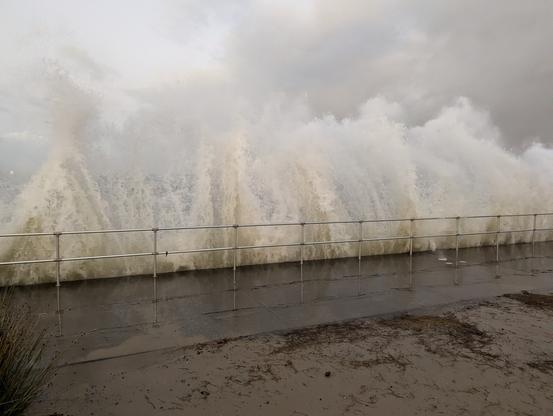 Botany bay foreshore at high tide with big swells coming in breaking in huge piles of water along the fence