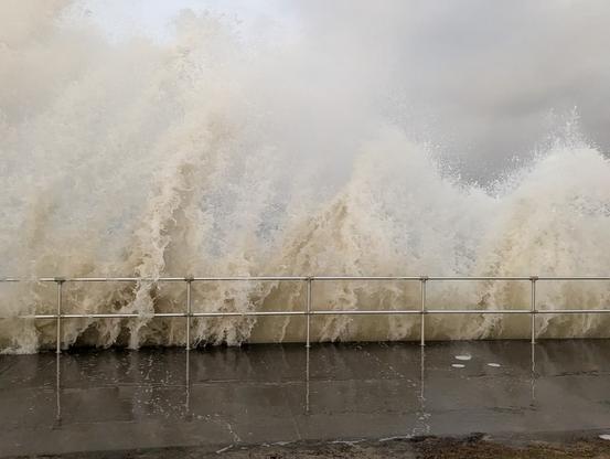 Botany bay foreshore at high tide with big swells coming in breaking in huge piles of water along the fence