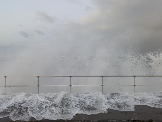 Botany bay foreshore at high tide with big swells coming in breaking in huge piles of water along the fence
