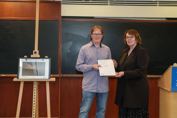 Tom O'Donoghue receives his prize from DIAS Registrar and CEO Dr Eucharia Meehan. His image "Sentinel" is on an easel to the left.