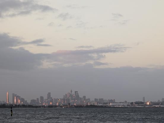 Sydney metropolitan skyline seen across the bay harbour at sunset with the late afternoon sunlight reflecting golden on the building facades