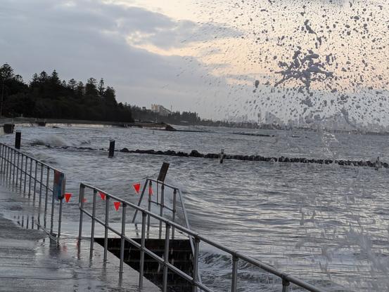 High tide big swells washing up on foreshore walls and shark pool fence