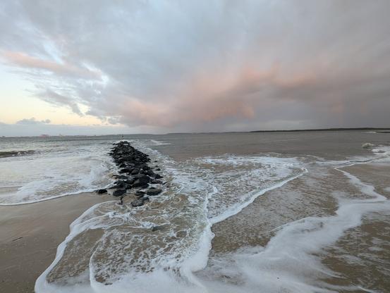 High tide big swells washing up on the beach under a pastel evening sky