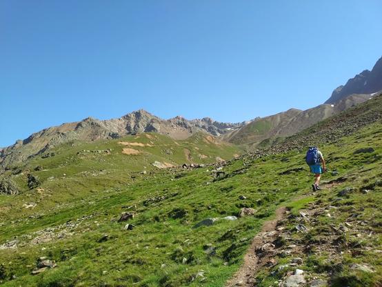 A hiker going up a trail in the European Central Alps.