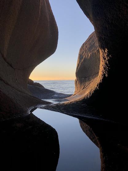 View to the open sea from a pothole whose interior are partially bathed in the light of the setting sun