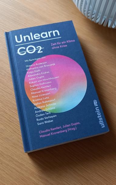 Das Buch "Unlearn CO2 - Zeit für ein Klima ohne Krise" liegt auf einem Holztisch.