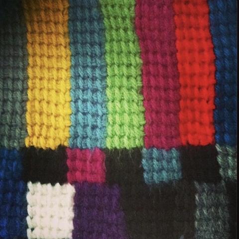 Knitted scarf where the ends feature a pattern in the design of a TV test pattern.