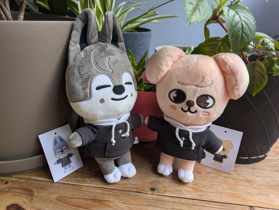Skzoo plush toys: Wolf Chan and PuppyM. They each wear a black hoodie with a white four-pointed star on the front