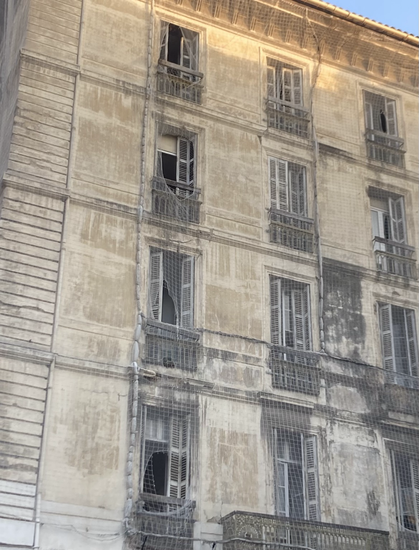 altes mehrstöckiges Haus, das mit Netzvorhang überzogen ist und auf Renovation wartet