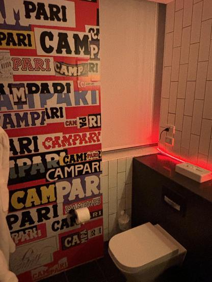 Bathroom with Campari poster on wall.