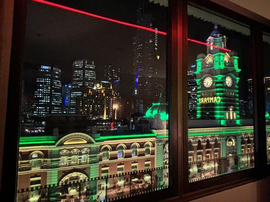 View of illuminated Flinders Street Station through window.