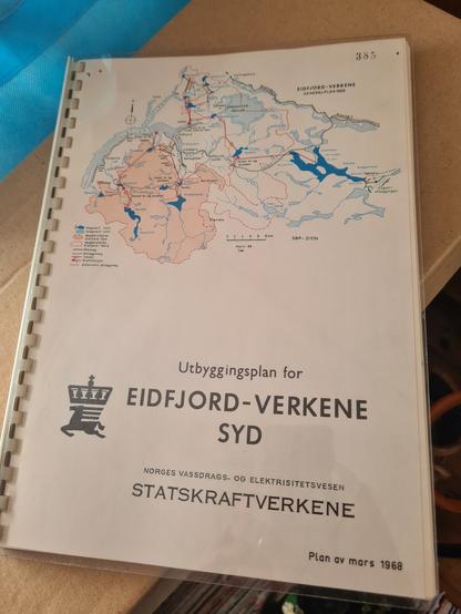 Hefte med plastspiral. Forsiden har et kart over planer for vannkraftutbygging mellom Eidfjord og Kinsarvik, i tillegg til kart over området nord for dette med Sima-kraftverkene. Tittel og undertitler: Utbyggingsplaner for EIDFJORD-VERKENE SYD. Norges vassdrags- og elektrisitetsverk. Statskraftverkene. Plan a  mars 1968.