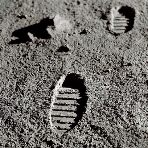 Footprints on the dusty surface of the moon with dark shadows from ridges of the astronaut’s moon boot sole.