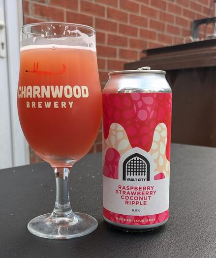 A stemmed beer glass full of an orange/red liquid with a tiny froth head plus the can which says Vault City Raspberry Strawberry Coconut Ripple
