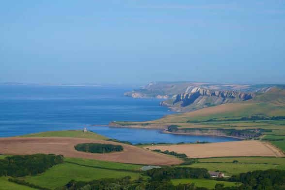 view looking westwards over Kimmeridge Bay and the Dorset coastline in morning light, taken from Smedmore Hill, Purbeck, Dorset, England. August 2024.