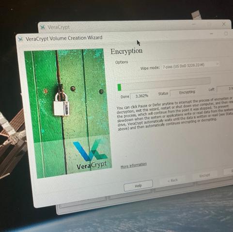 Photo of VeraCrypt beginning to encrypt the drive on a 2017-vintage HP Spectre x360. The screen wallpaper visible behind that app's window is a picture of the International Space Station with Earth visible below it.