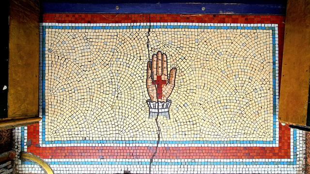 A mosaic threshold at the entrance to a Glasgow bar with a picture of a hand with a cross on its palm in the middle of it.