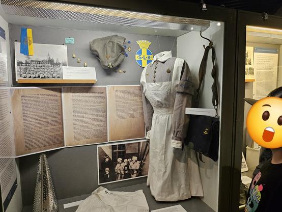 A display of the uniform of ww2 lottakaren, a voluntary organisation connected to the war that Jens gran was part of. A kid with his face censored is on the right