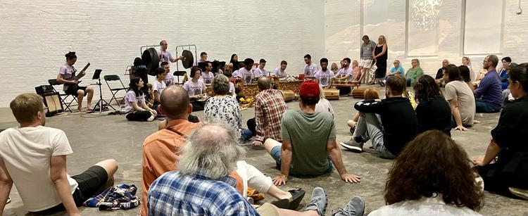 Audience scattered on floor watching gamelan orchestra