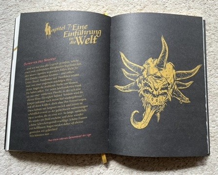 Doppelseite: „Eine Einführung in die Welt“ - Gelb auf Schwarz gedruckt, eine einfarbige Illustration eines Dämonenschädels mit herausgestreckter Zunge.