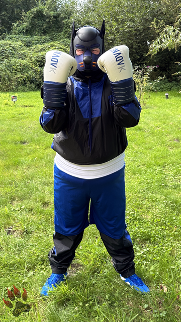 human pup in sweatsuit and boxing gear (boots, trunks and gloves) standing outside in the garden, hands up to defend