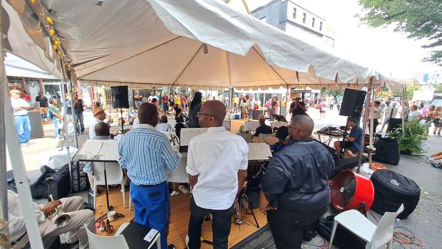 Behind a jazz group under a tent with a couple dancing.