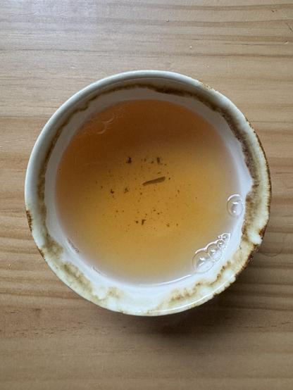 Teacup filled with golden puerh tea on a wooden table