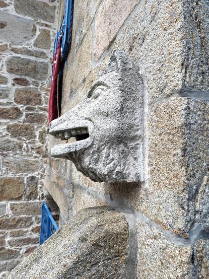 Profile view of the animal head. It looks more like a wolf in this angle, with a triangular shape leading to the nose. The bottom of the head, below its open mouth is sculpted to resemble fluffy fur.