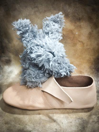 A photo of a toy bunny sitting on a medieval leather shoe