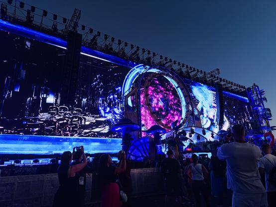 zdjęcie sceny głównej Sunrise Festival 2024 - olbrzymi, szeroki LEDowy ekran, oświetlony animacją w tonacji niebiesko-fioletowej, późny wieczór