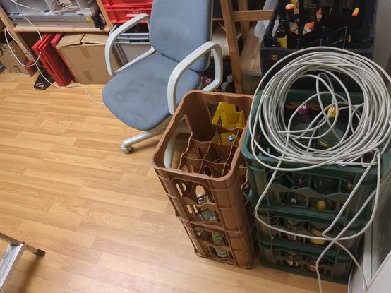 A LAN cable on some empty beverage crates. The LAN cable is going into the shelve where a server is laying below some crates.