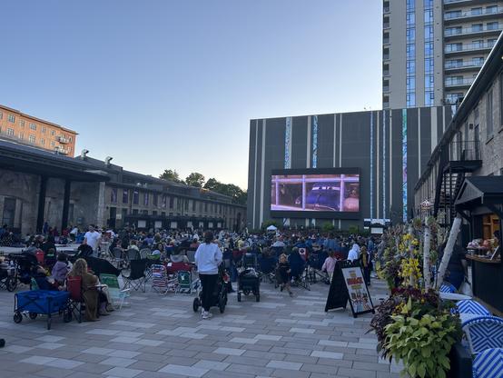 Picture of a crowd of families watching a giant outdoor tv screening of Cars.