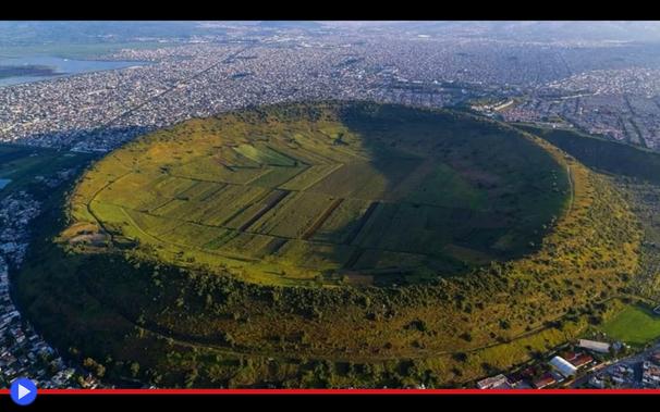 Veduta aerea di un cratere coltivato circondato da numerosi edifici cittadini.